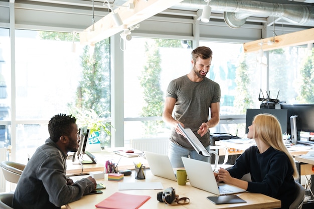 Free Photo smiling young colleagues sitting in office coworking