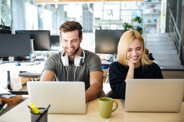 Free photo smiling young colleagues sitting in office coworking