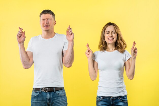 Smiling young couple crosses fingers in anticipation of something pleasant