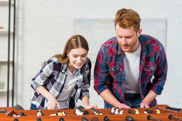 Smiling young couple playing the indoor soccer game at home