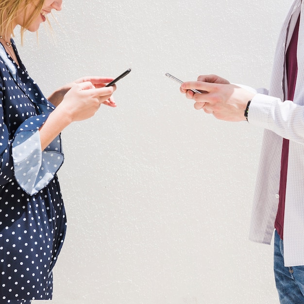 Free Photo smiling young couple sending messages with mobile phone