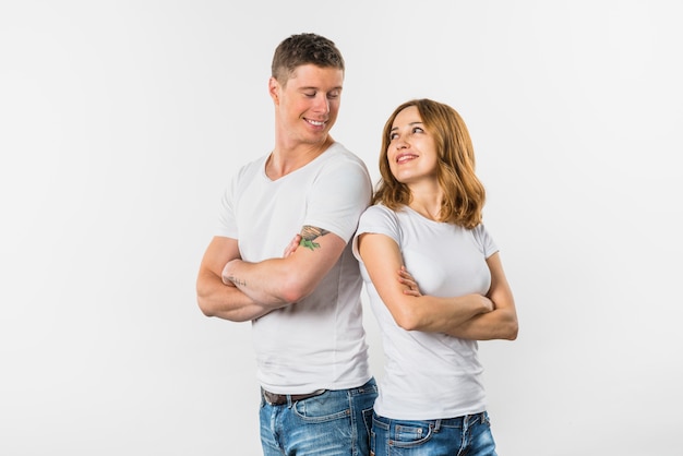 Smiling young couple standing back to back looking at each other against white background