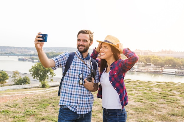 Free photo smiling young couple taking selfie on cellphone at outdoors