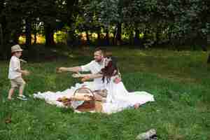 Free photo smiling young father and mother resting on plaid in the park while their little child running into their arms. family and leisure concept