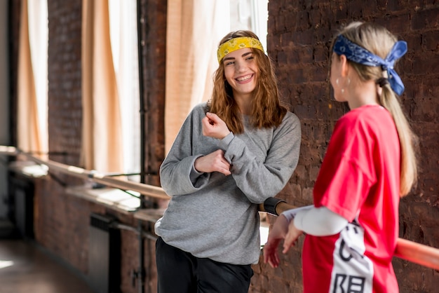 Smiling young female dancer standing near the barre in the dance studio