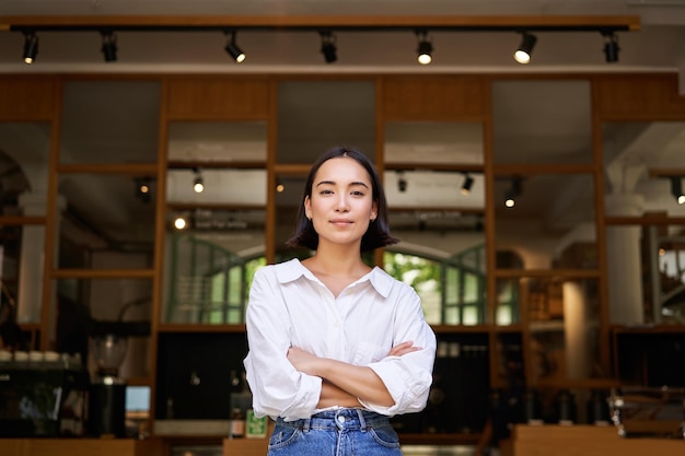 Smiling young female manager cafe owner cross arms on chest looking confident standing in front of r