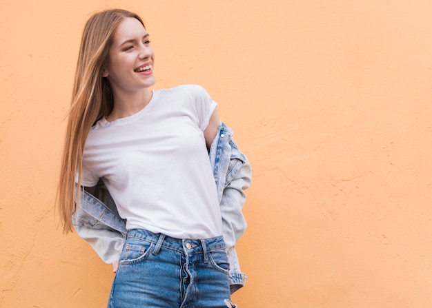 Smiling young female model posing on beige wall textured