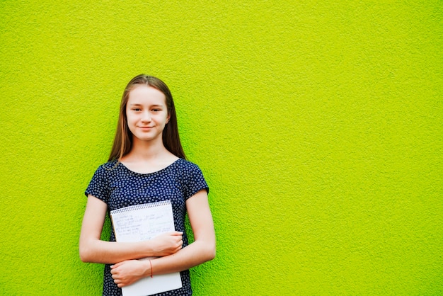 Free Photo smiling young girl posing with notepad