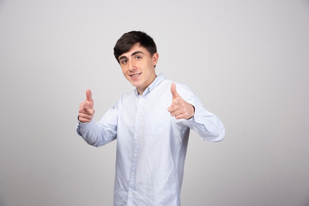 A smiling young guy model standing and showing thumbs up