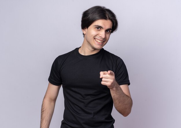 Smiling young handsome guy wearing black t-shirt showing you gesture isolated on white wall