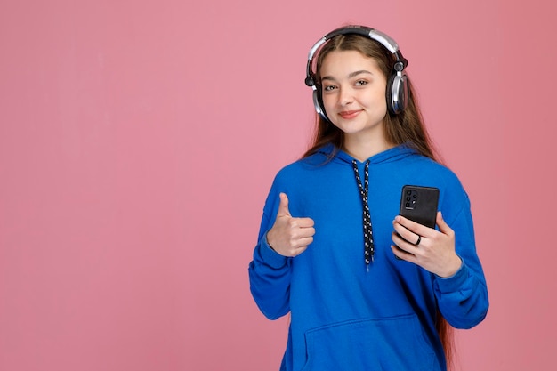 Free Photo smiling young lady keeping thumb up while listening to music with headphones