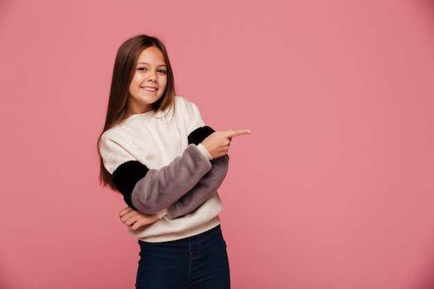 Smiling young lady pointing at copy space and looking