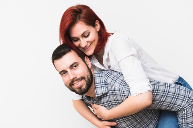 Smiling young man carrying wife on his back