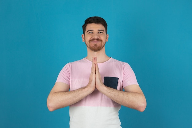 Free Photo smiling young man doing meditation on a blue.