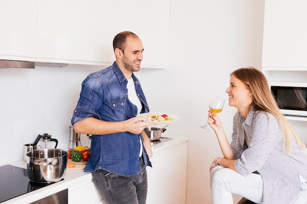 Smiling young man eating salad and his wife drinking alcohol