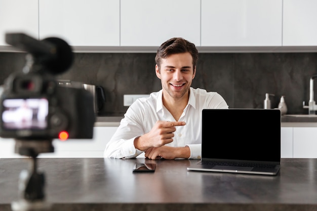 Smiling young man filming his video blog episode