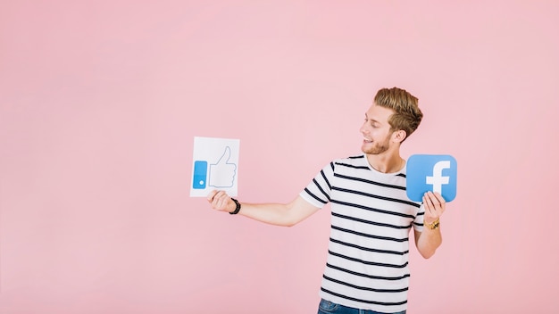 Smiling young man holding like and facebook icon