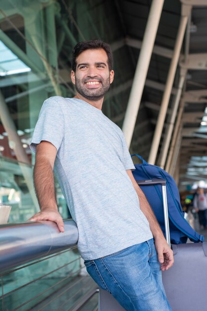 Smiling young man leaning on metal railing at airport