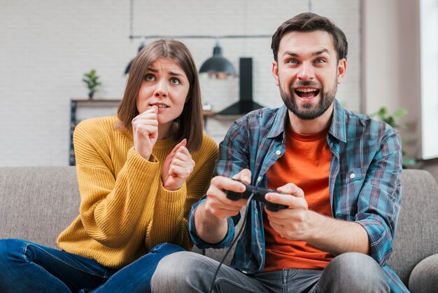 Smiling young man playing the video game with her wife