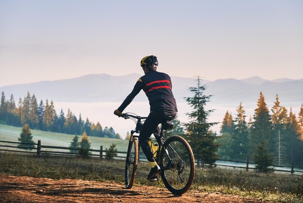 Smiling young man riding bicycle on mountain road