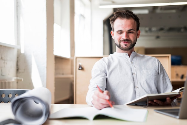 Smiling young man sitting on chair working in office