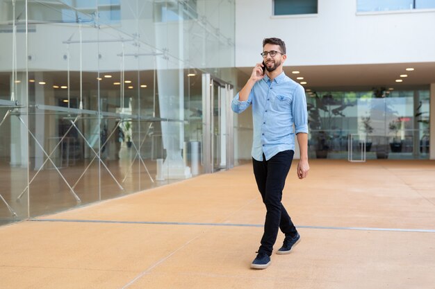 Smiling young man talking by cell phone