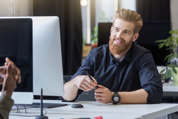 Free Photo smiling young man talking to his colleague