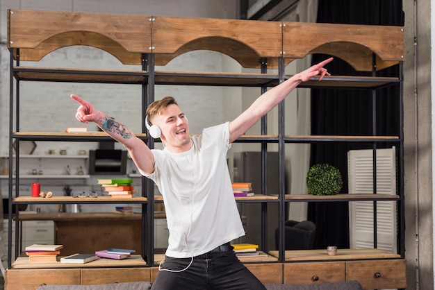 Free photo smiling young man with headphone on his head dancing in front of showcase