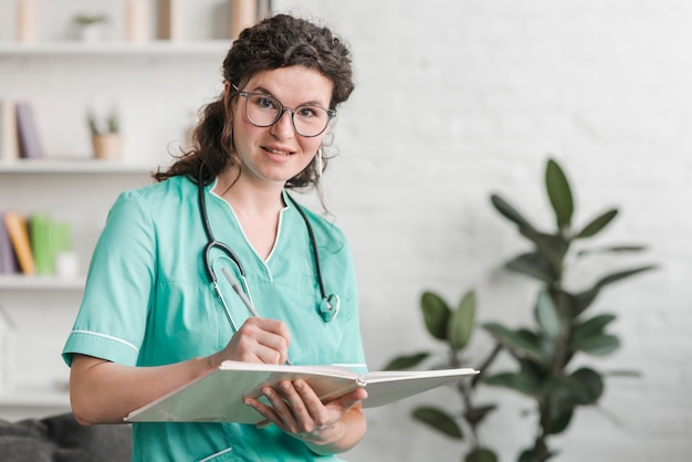 Free photo smiling young nurse with book and pen in the clinic