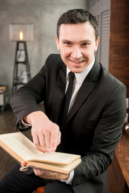 Free Photo smiling young pleased businessman offering book