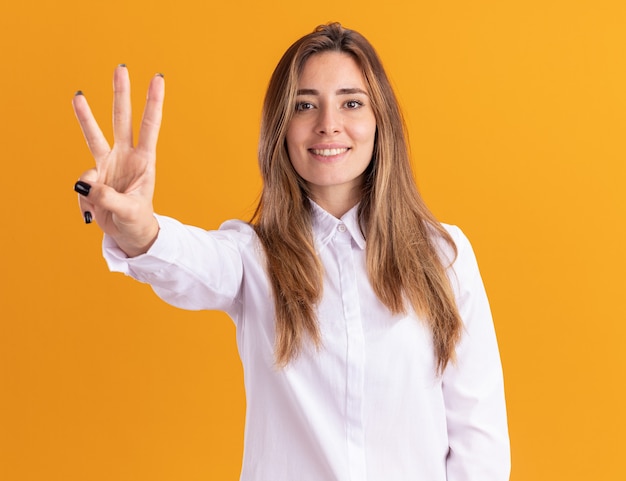 Free photo smiling young pretty caucasian girl gestures three with fingers on orange