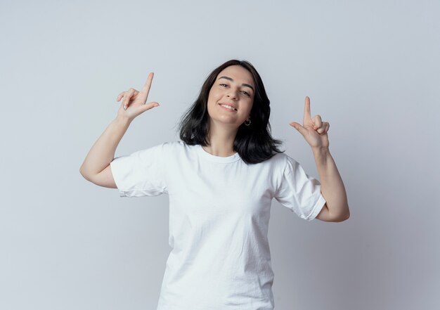 Smiling young pretty caucasian girl pointing with fingers up isolated on white background with copy space