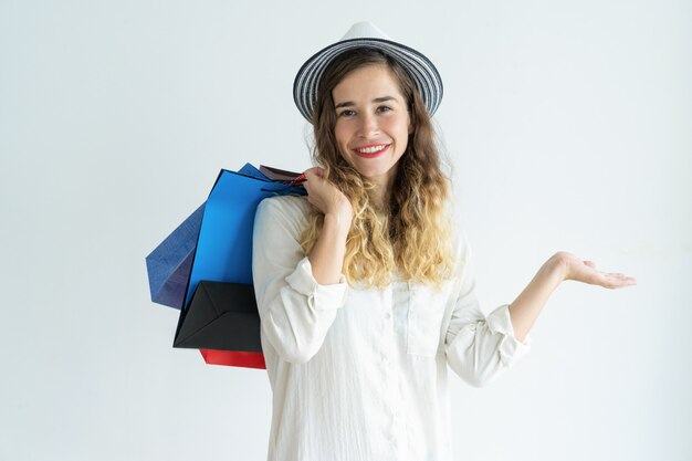 Smiling young pretty woman holding shopping bags, wearing hat