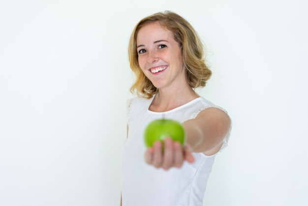 Smiling young pretty woman offering blurred green apple