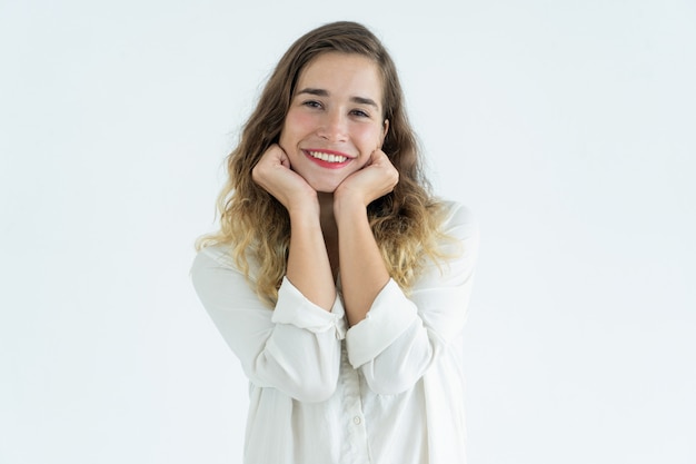 Smiling young pretty woman standing and leaning head on hands. 