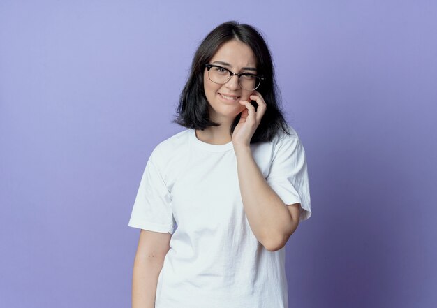 smiling young pretty woman wearing glasses putting hand on cheek