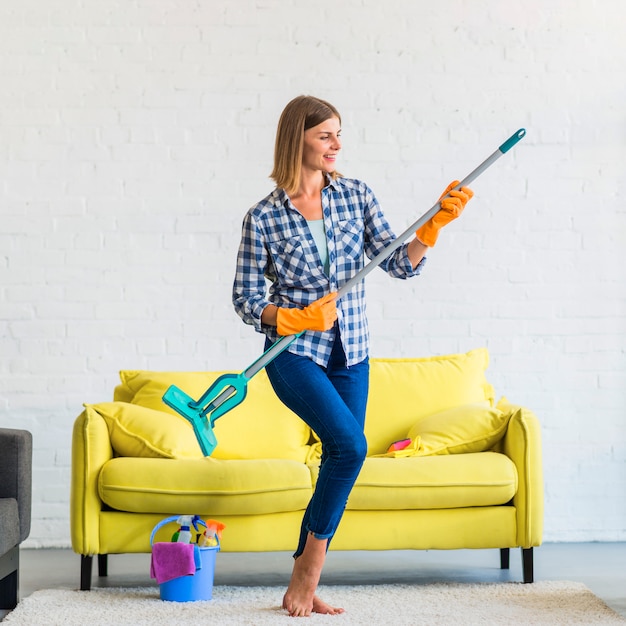 Smiling young woman acting like playing guitar in the living room