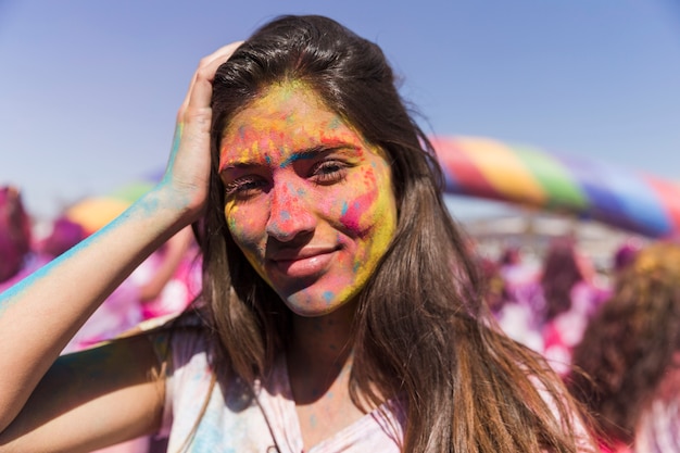 Free photo smiling young woman covered her face with holi color