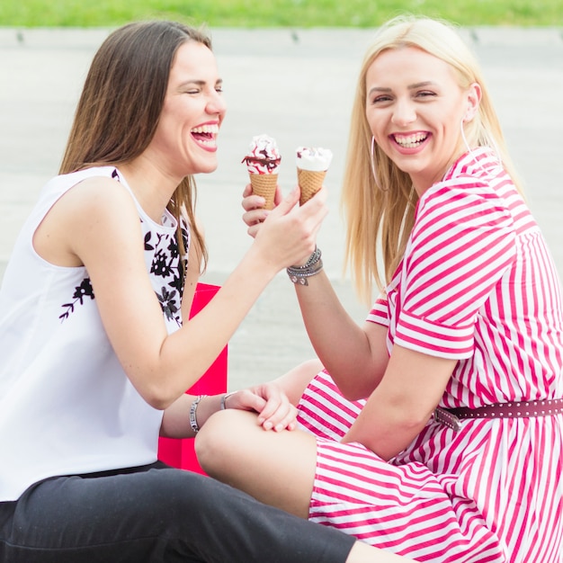 Free photo smiling young woman eating icecream cone