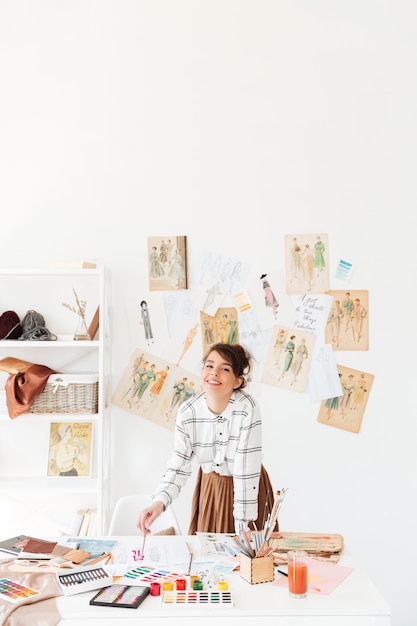 Free Photo smiling young woman fashion designer standing at her workplace