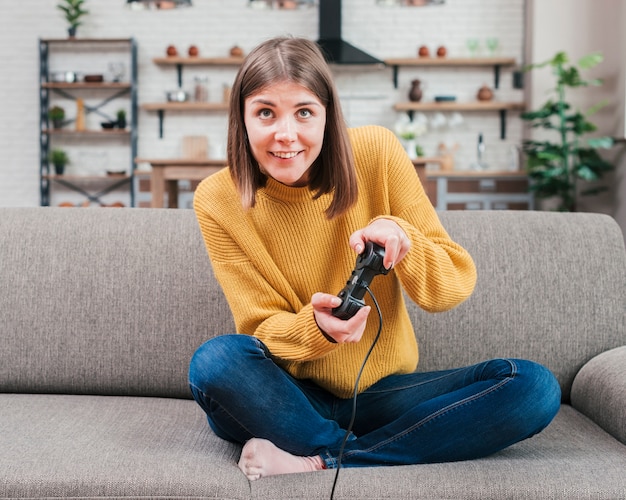 Free photo smiling young woman having fun playing video console game at home