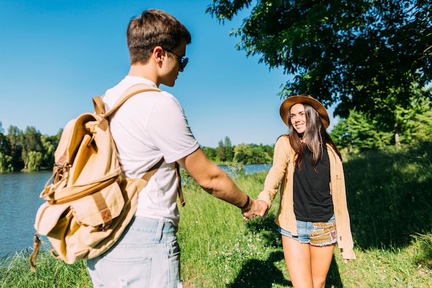 Free photo smiling young woman holding boyfriend's hand in the park