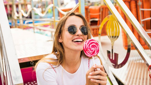 Smiling young woman holding red and pink lollipop in hand