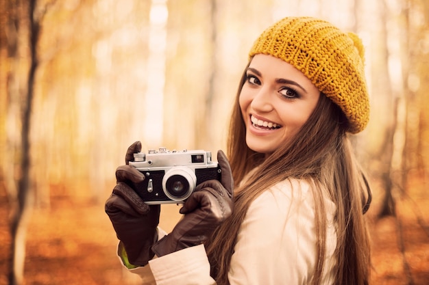 Smiling young woman holding retro camera