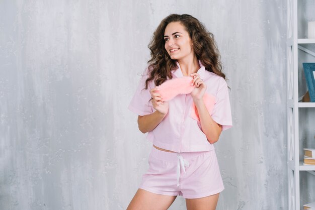 Smiling young woman holding sleeping eye mask