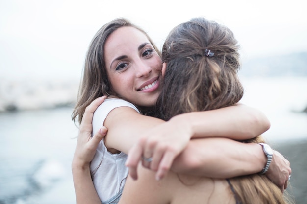 Free Photo smiling young woman hugging her female friend