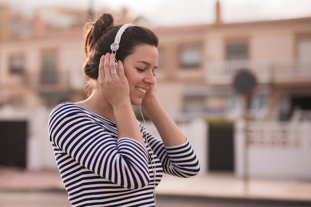 Free photo smiling young woman listening music on headphone