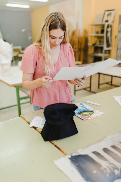 Free photo smiling young woman looking at paintings in the workshop