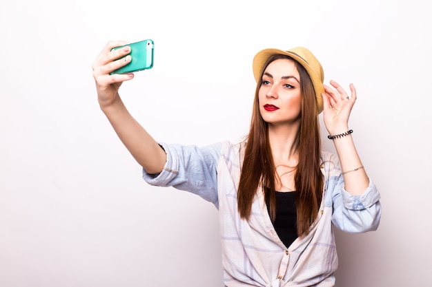 Smiling young woman making selfie photo on smartphone over gray