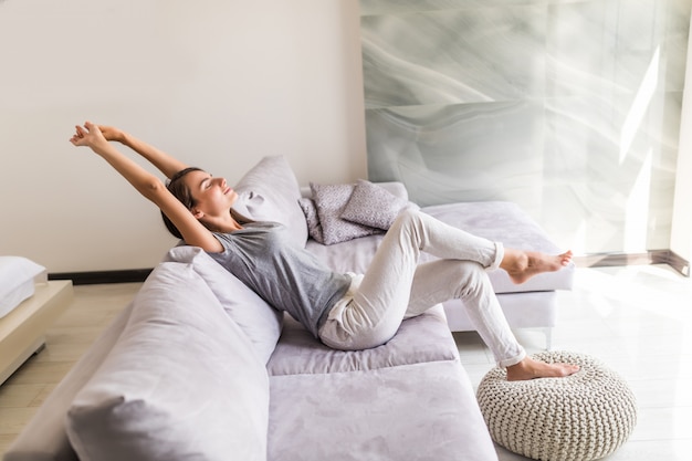 Free photo smiling young woman relax lying on couch